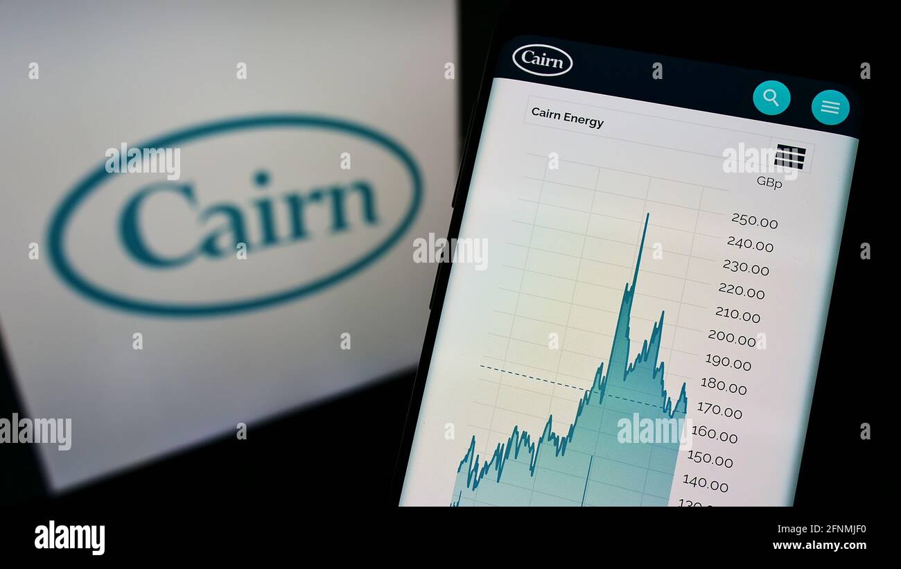 Person holding cellphone with website and stock chart of oil and gas company Cairn Energy plc on screen with logo. Focus on center of phone display. Stock Photo