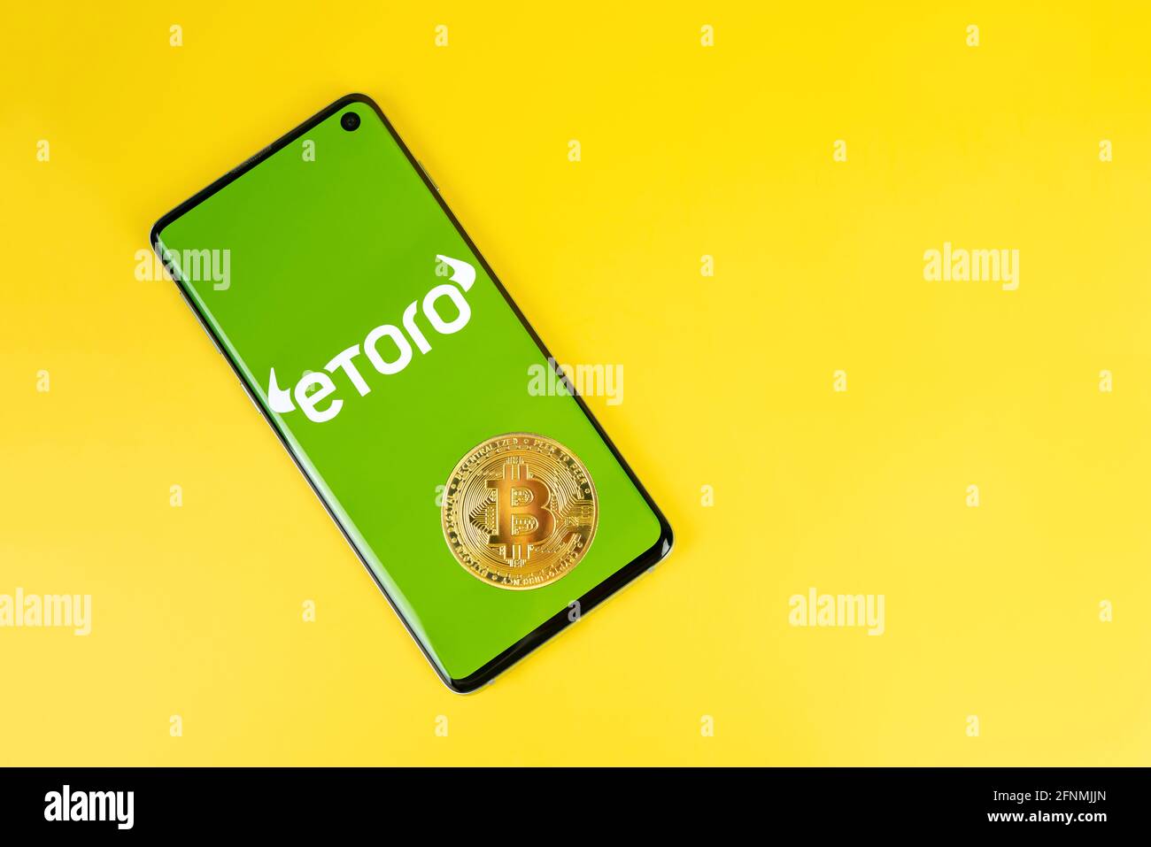 Smartphone with Etoro logo with Bitcoin coin on yellow background. Trading  platform, investing in stocks and cryptocurrencies Stock Photo - Alamy