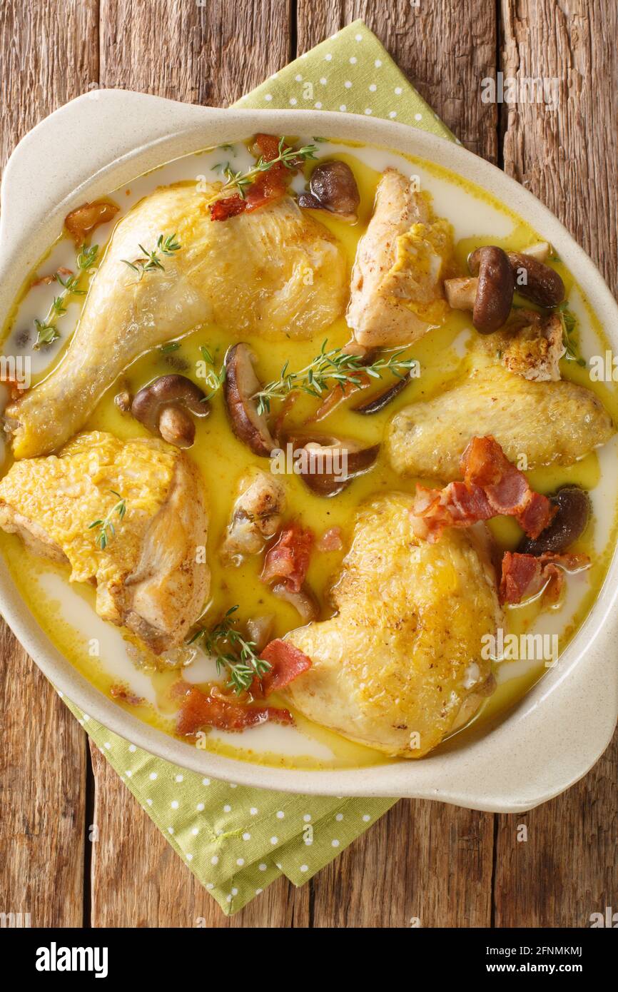 French Coq au Riesling chicken in wine Recipe closeup in the bowl on the table. Vertical top view from above Stock Photo