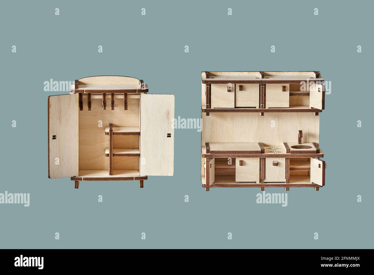 Cute small toy wardrobe and kitchen set made of ply wood details cut with laser machine tool isolated on green background Stock Photo