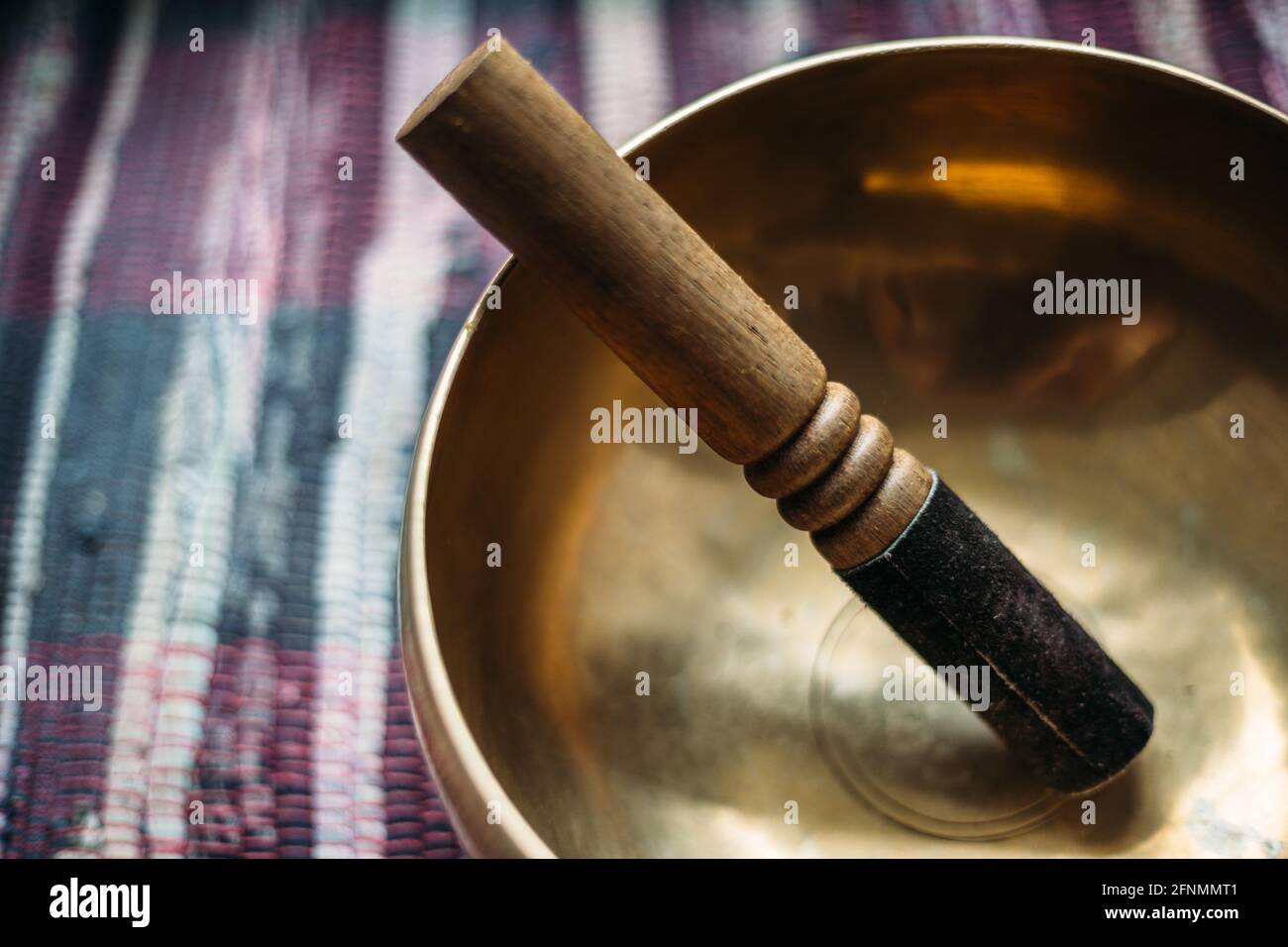 Tibetan singing bowl with a stick on a handmade woven carpet. Stock Photo