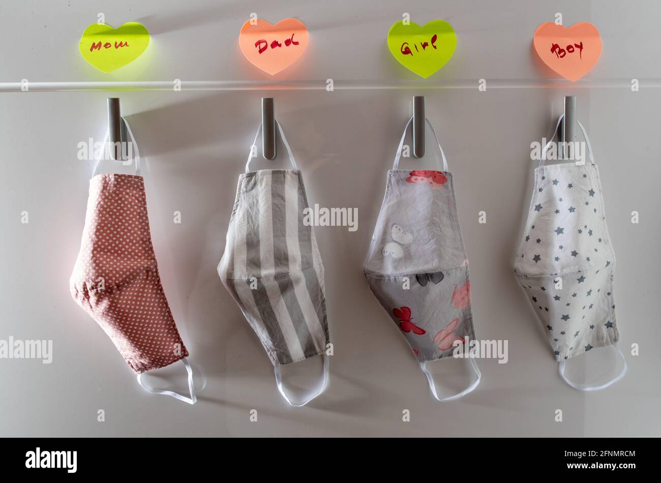 Fabric protective masks hanging on wall at home entrance with family