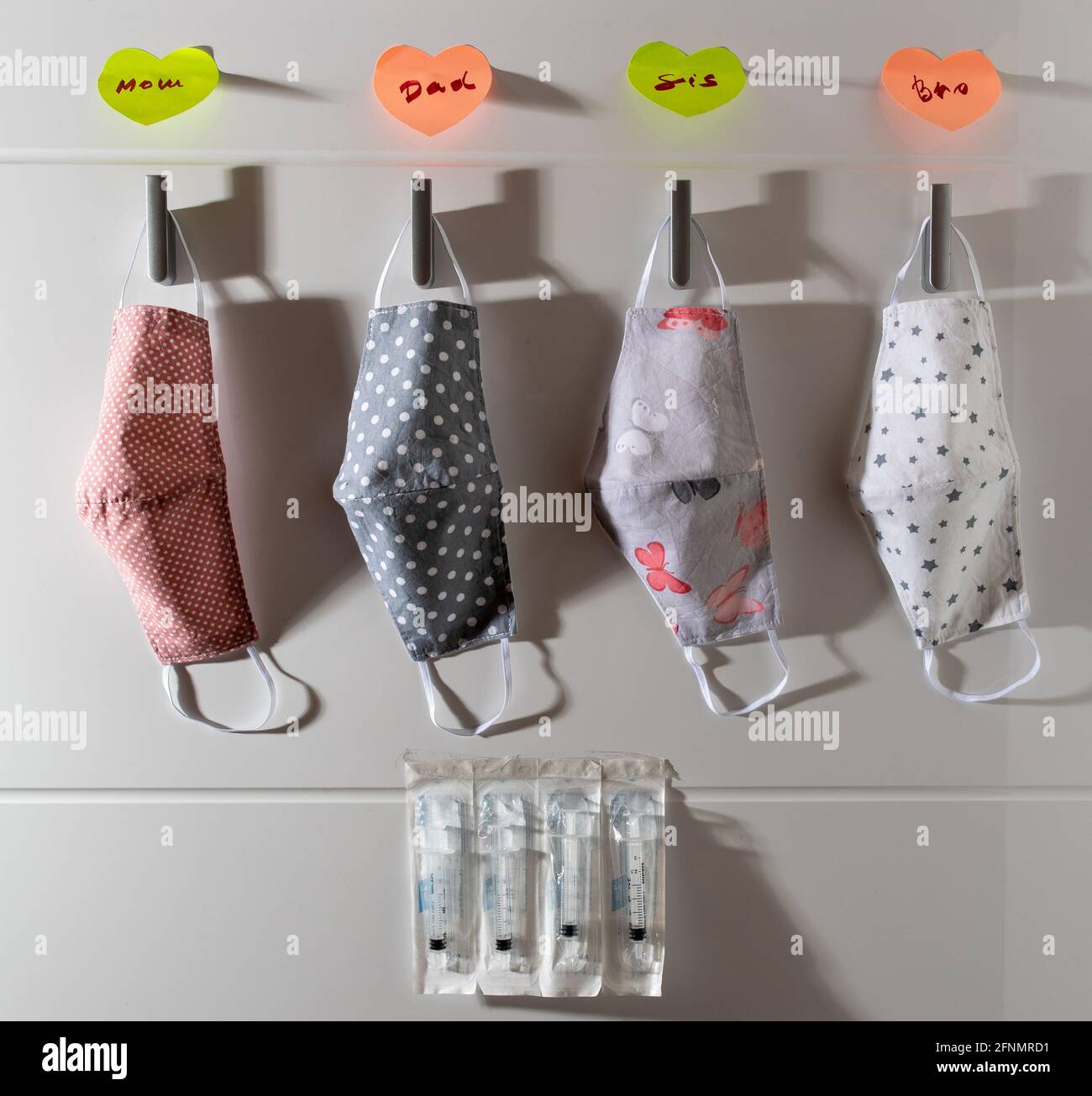 Fabric protective masks hanging on wall at home entrance with labels on