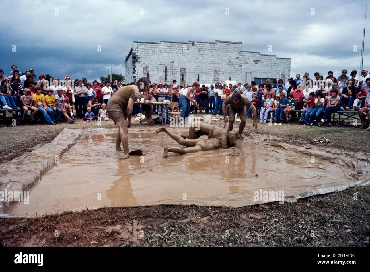 Mud wrestling, Fun in the mud, Muddy fair day goers, Simcoe Ontario Canada 1982. Stock Photo