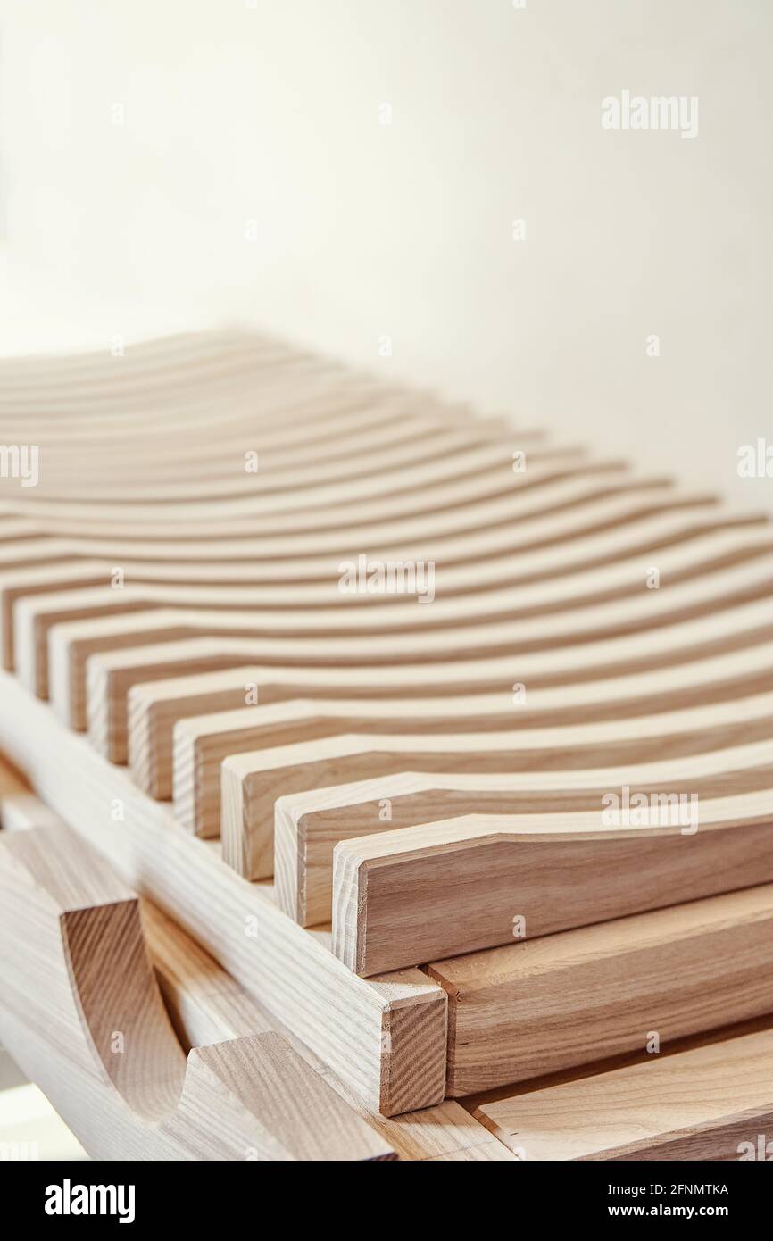 Stylish dishes drying rack made of light solid wood ash timber near plywood cabinet in modern carpentry workshop extreme close view Stock Photo