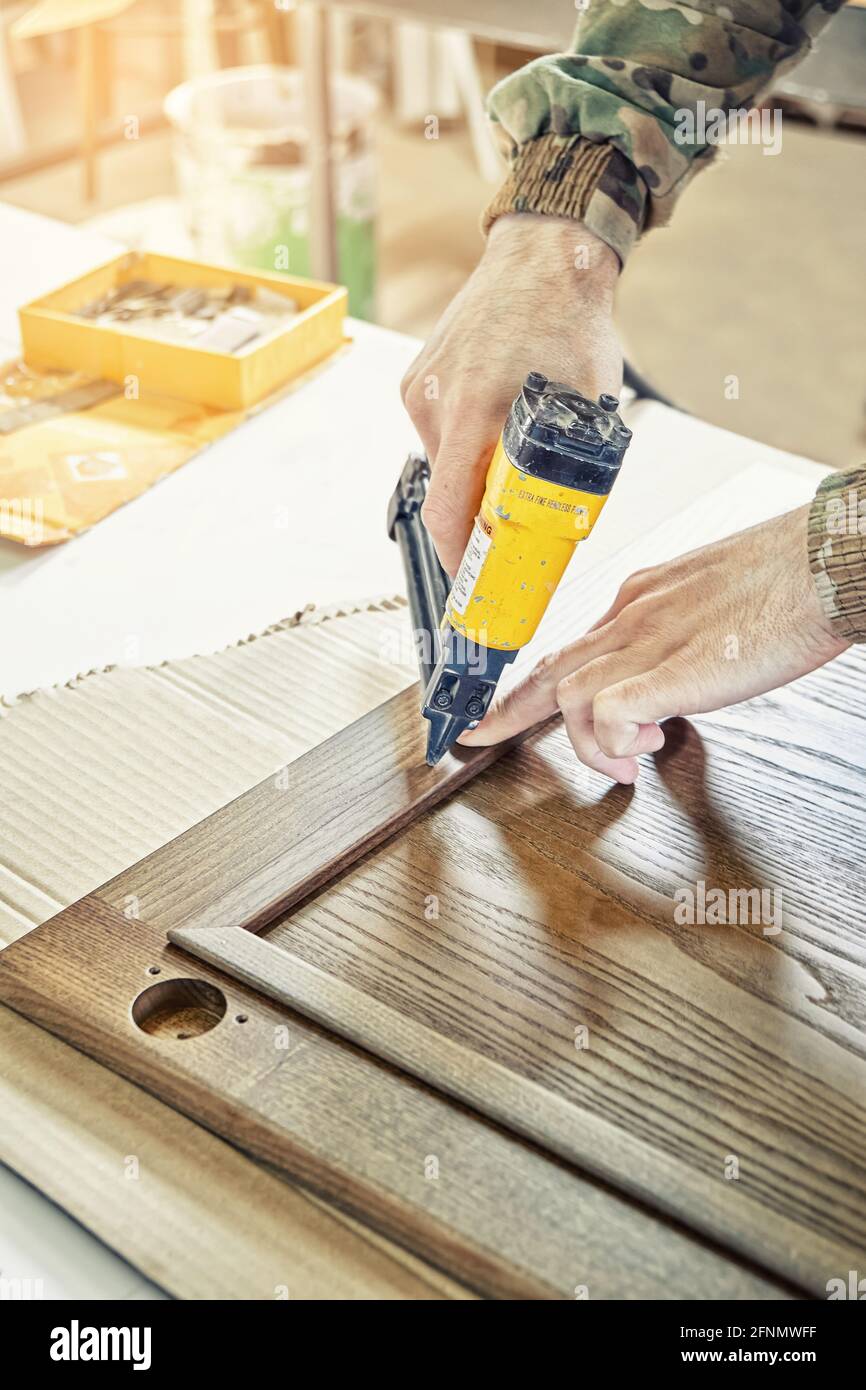Skilled carpenter assembles wooden door for kitchen fixing