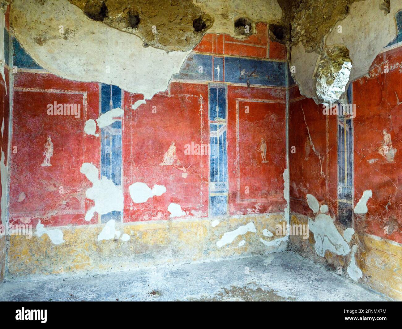 Room decorated in the fourth style with red panels on a dark blue ground above a lower red frieze. The panels feature small cameos of soldiers in different stances. House of Octavius Quartio - Pompeii archaeological site, Italy Stock Photo