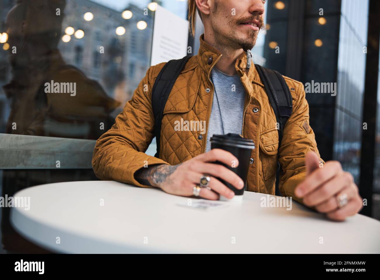Bearded tattooed man having coffee outdoors alone Stock Photo