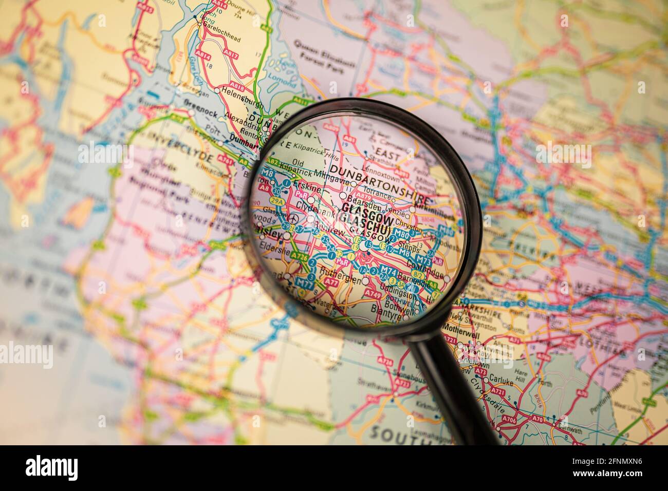 Close-up map of Glasgow through black magnifying glass, city in Scotland, United Kingdom Stock Photo
