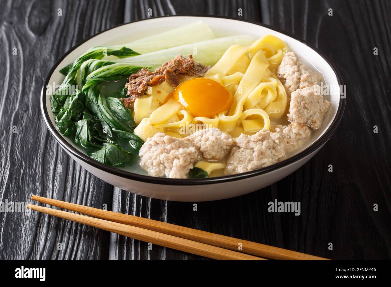 Singapore style homemade noodle soup with fried anchovies, meatballs