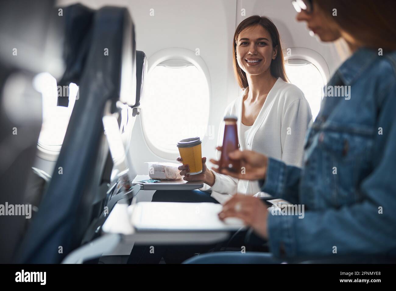 Two women raising their drinks on an airplane Stock Photo Alamy