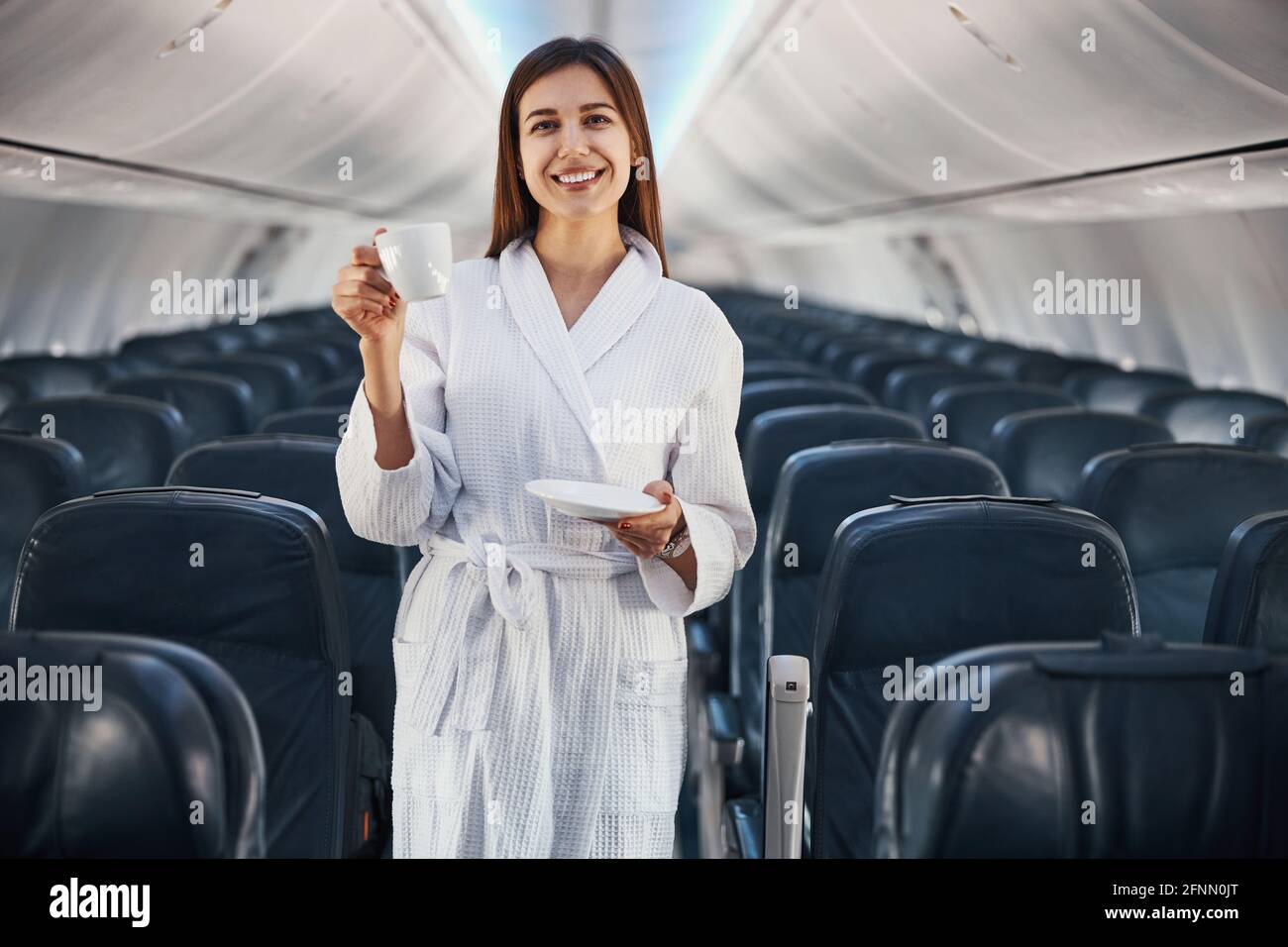 Joyful woman in gown doing cheers gesture with coffee cup Stock Photo