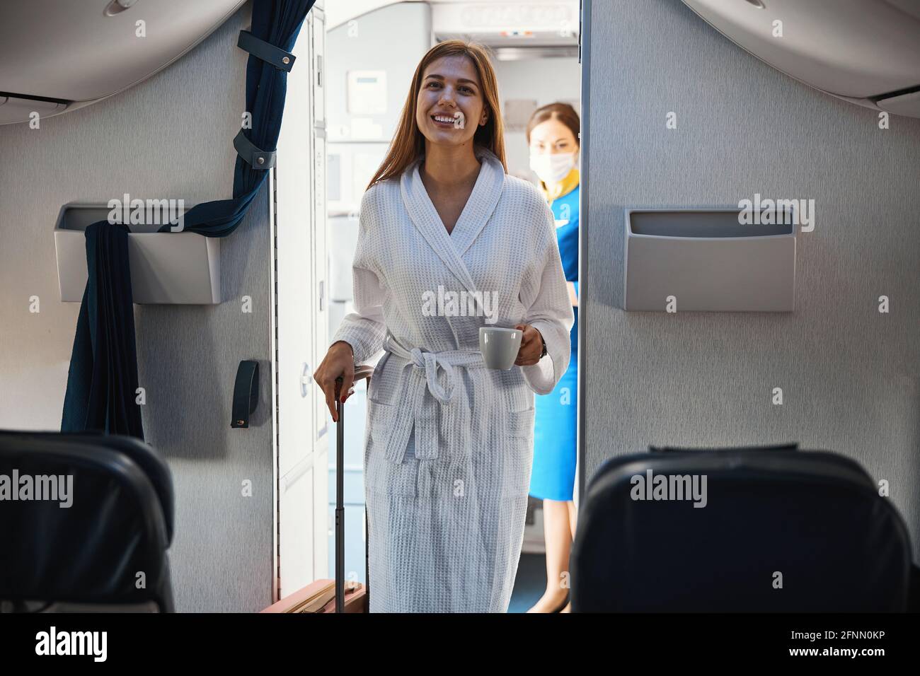 Relaxed female coming inside plane cabin in robe with coffee Stock ...