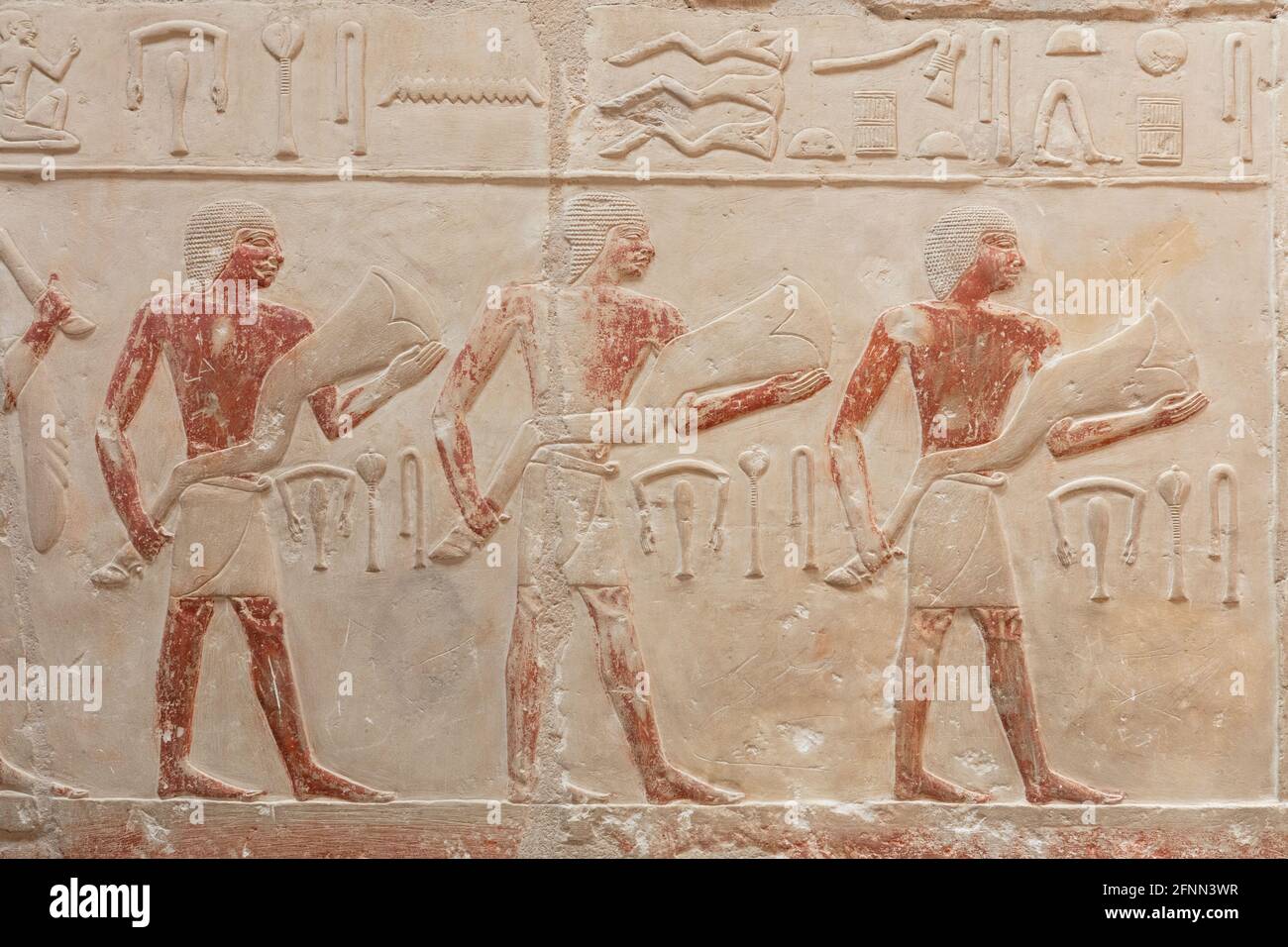 Mysterious egyptian engraved figures on the light wall. Stock Photo