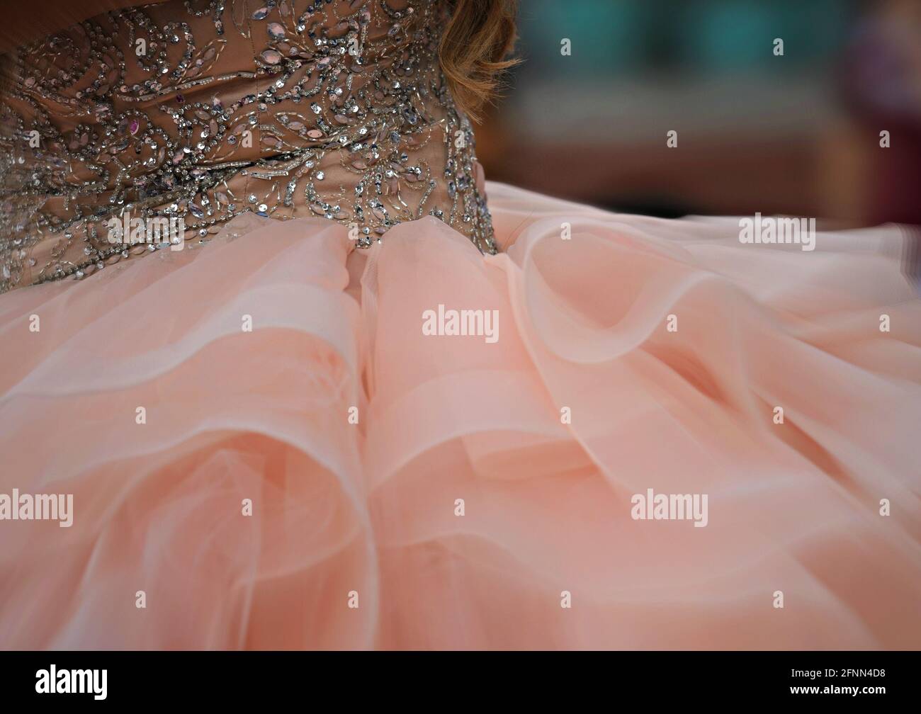Young girl wearing a formal pastel peach color Quinceañera gown