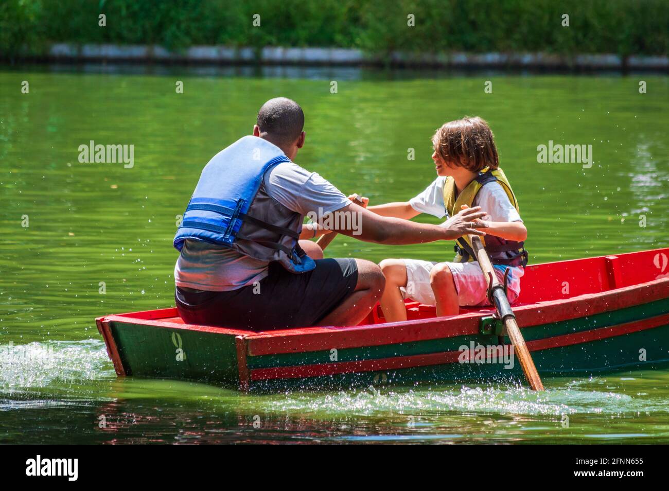 Black man and white boy rowing a boat at Parque Municipal Américo Renné Giannetti, Belo Horizonte. Stock Photo
