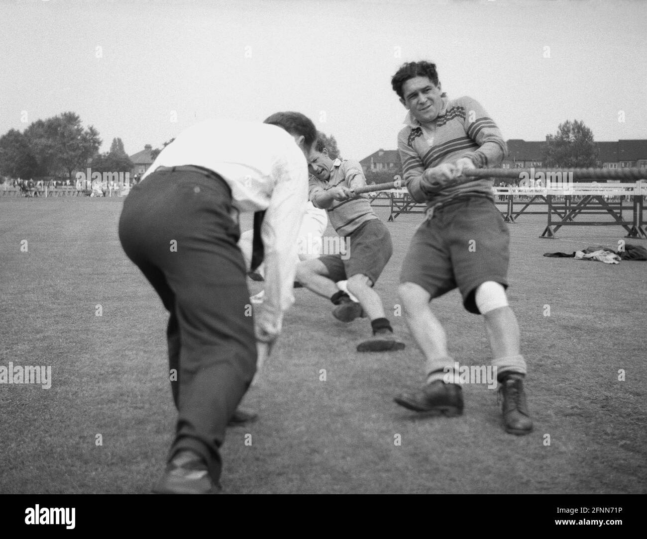 1954, historical, outside in a field, at a civil service sports day, in a tug-of-war contest, a man urging his team to pull harder on the rope, England, UK. An ancient sport, Tug of War which was in the summer Olympic games from 1900 to 1920, is a test of strength between two teams with the goal being to bring the rope a certain distance in one direction against the force of the opposite team's pull. Strong leg and arm muscles are needed. Stock Photo