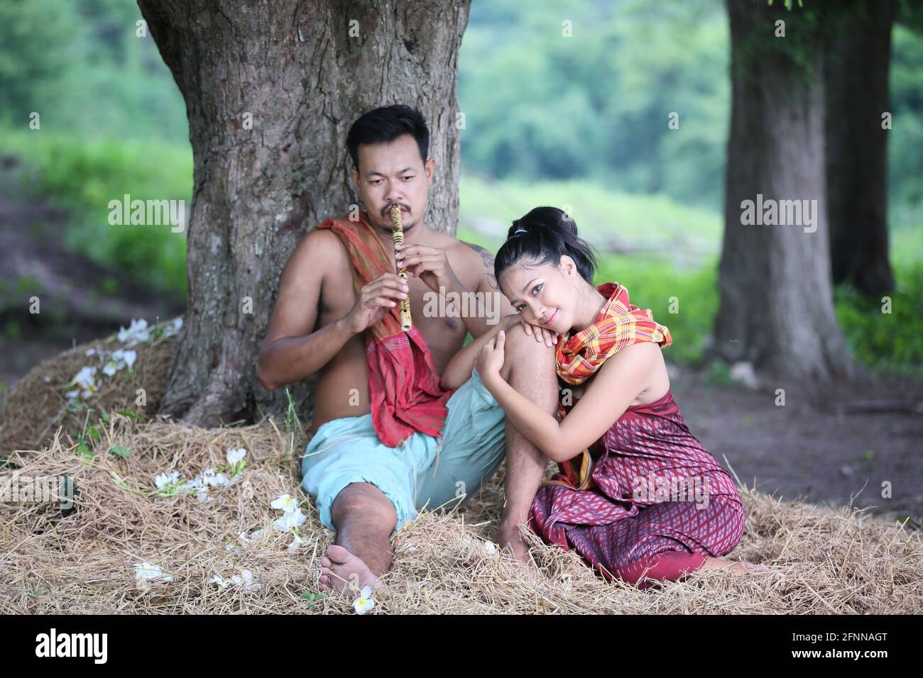 Couple love of Asian Young man and women sitting under tree against buffalo and natural background, rural way of life in the Northeast of Thailand. A Stock Photo