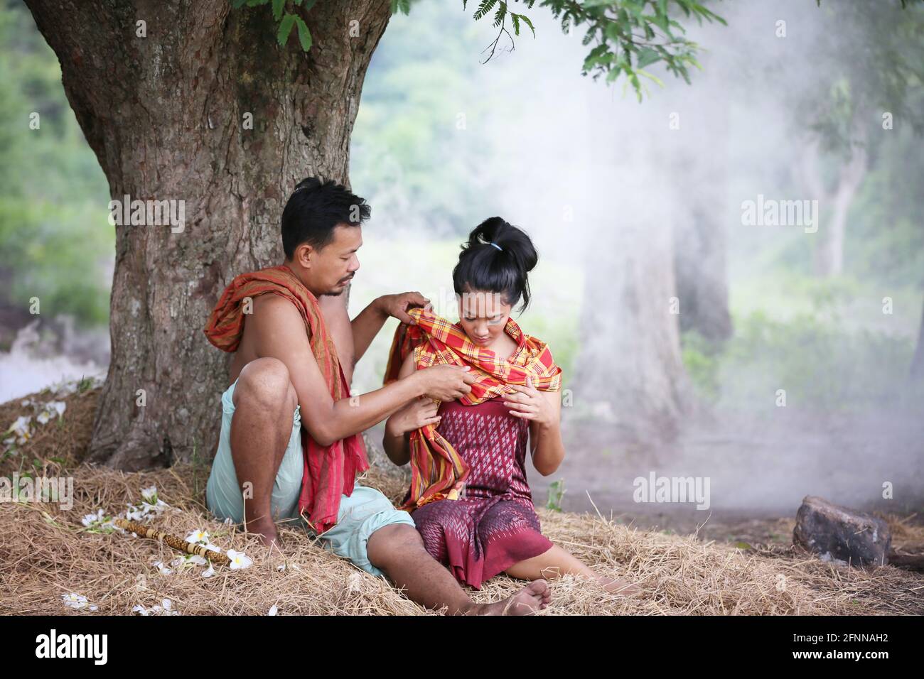 Couple love of Asian Young man and women sitting under tree against buffalo and natural background, rural way of life in the Northeast of Thailand. A Stock Photo