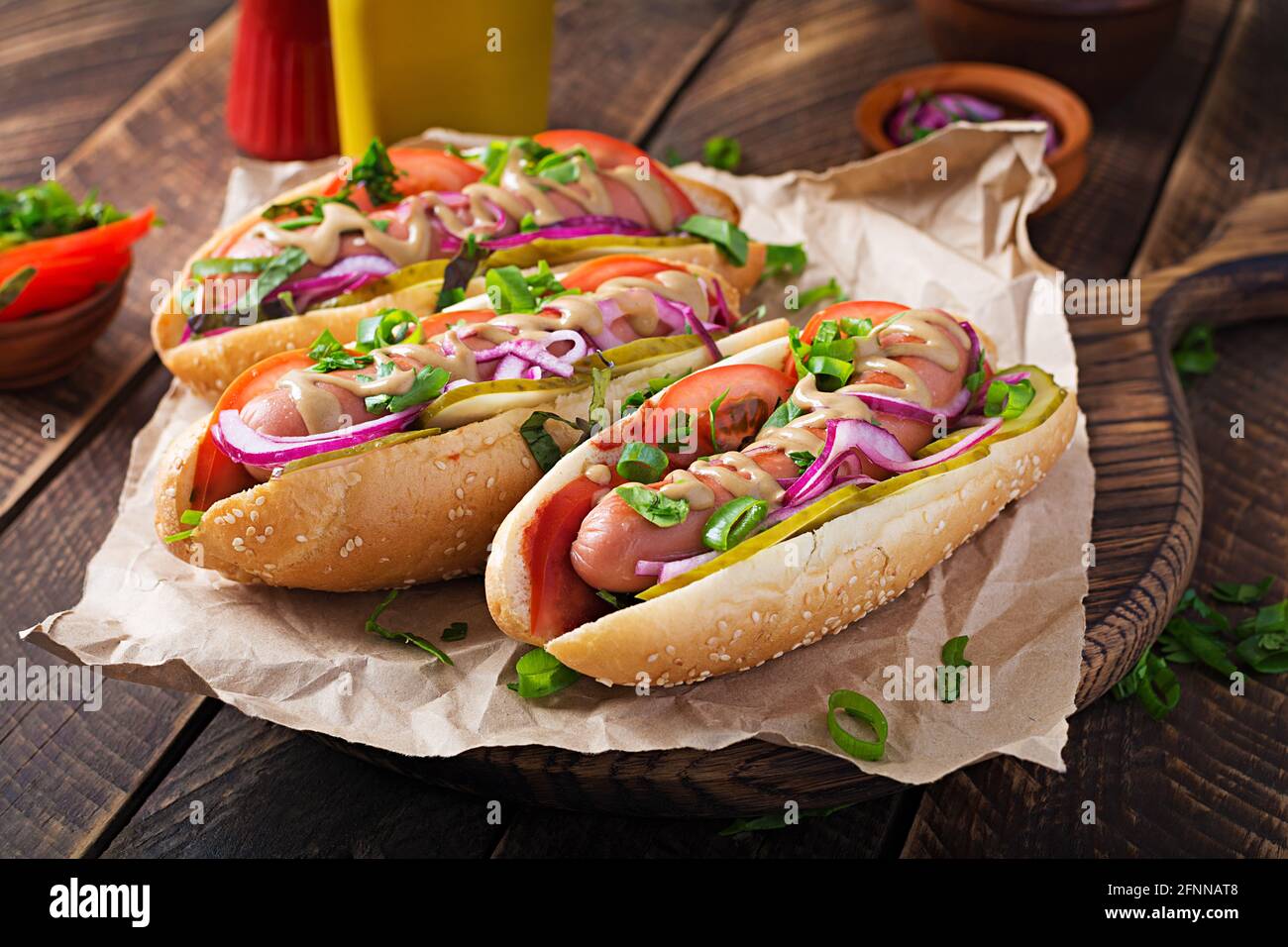 Hot dog with pickles, tomato and lettuce on wooden background. Hotdog