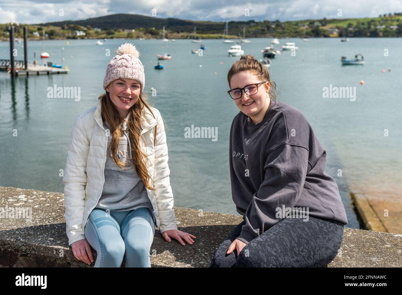 Schull, West Cork, Ireland. 18th May, 2021. The sun shone on Schull today which prompted many locals and visitors to make the most of the nice weather before the rain arrives over the next few days. Enjoying the sunshine on Schull Pier were Anna O'Regan and Ciara Goggin from Schull. Credit: AG News/Alamy Live News Stock Photo