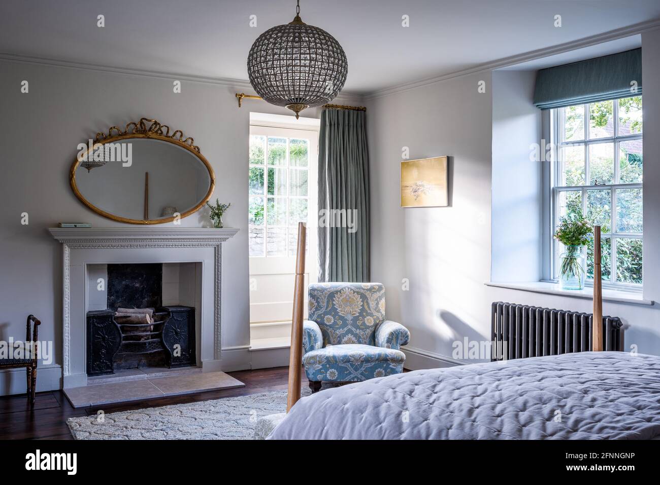 Mirror above fireplace with upholstered armchair in restored Jacobean Wool Merchant's house, Somerset. Stock Photo