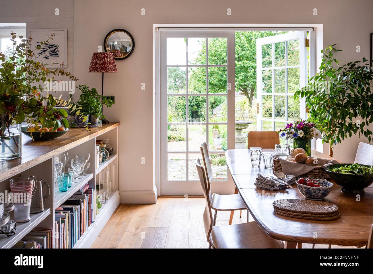 Dining room bookshelf with open door to garden in 19th century Victorian cottage. Stock Photo