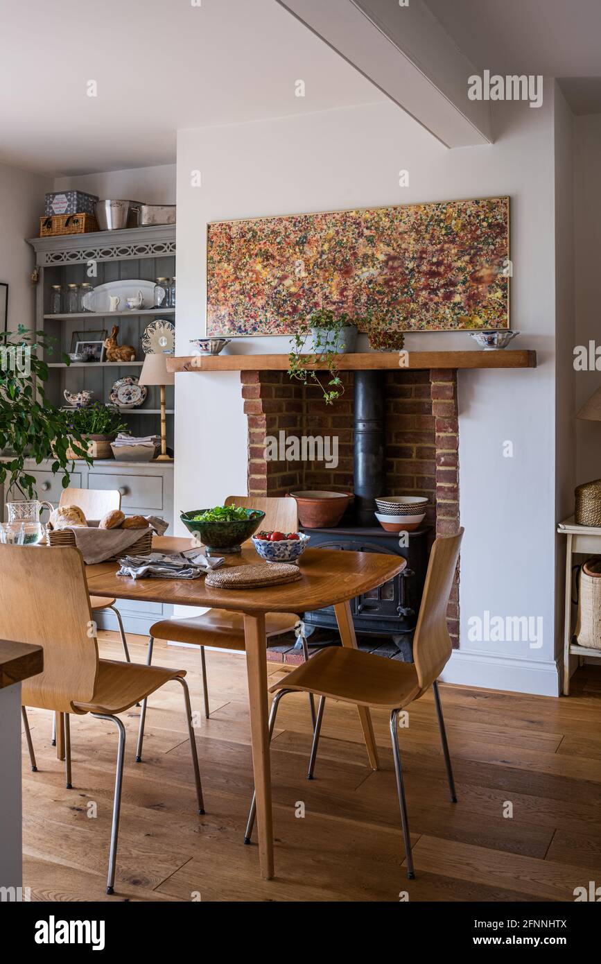 Modern art above woodburner in dining room of 19th century Victorian cottage. Stock Photo