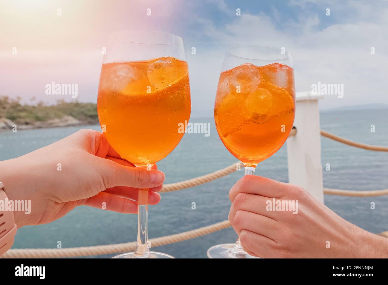 Two hands holding drinks over the sea Stock Photo Alamy