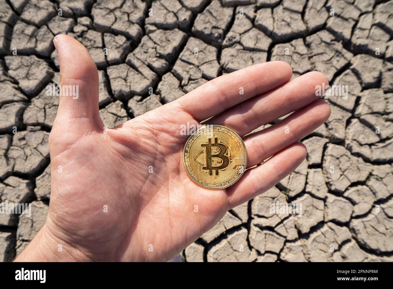 BITCOIN OVER DRY LAND IN HAND SYMBOLIZING GLOBAL WARMING AND CRYPTO MINING  Stock Photo - Alamy
