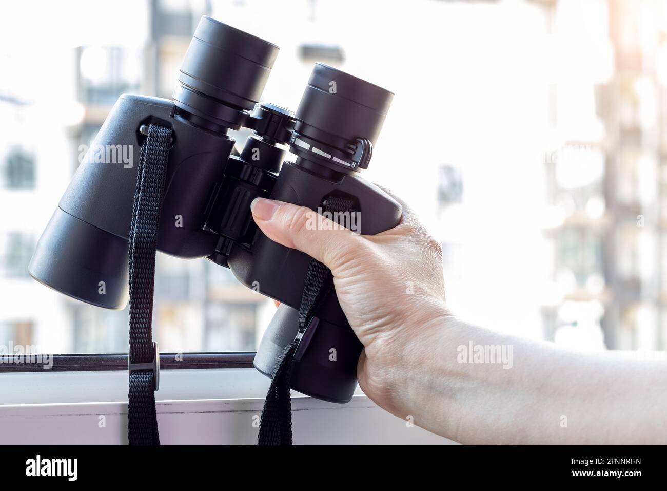 Hand holding black binoculars against a blurred background Stock Photo