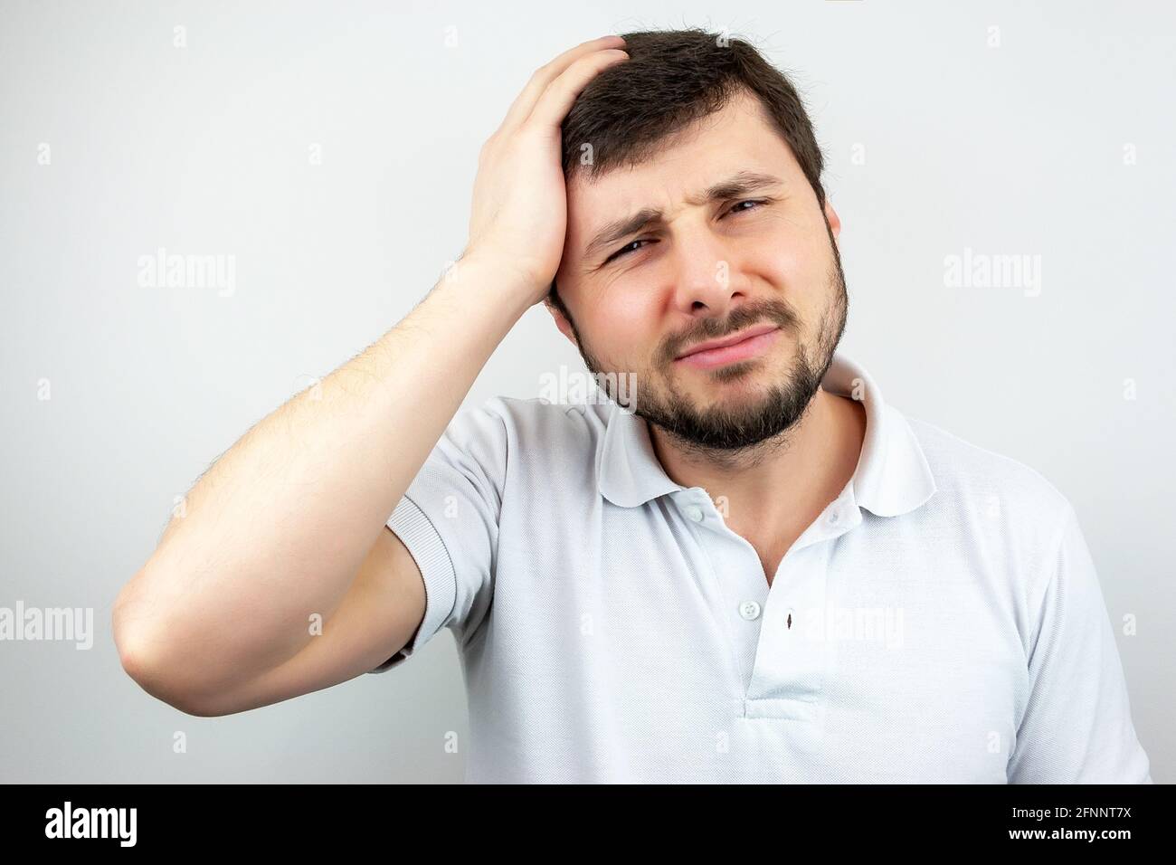 Portrait of a handsome bearded man with narrowed eyes and lips, holding