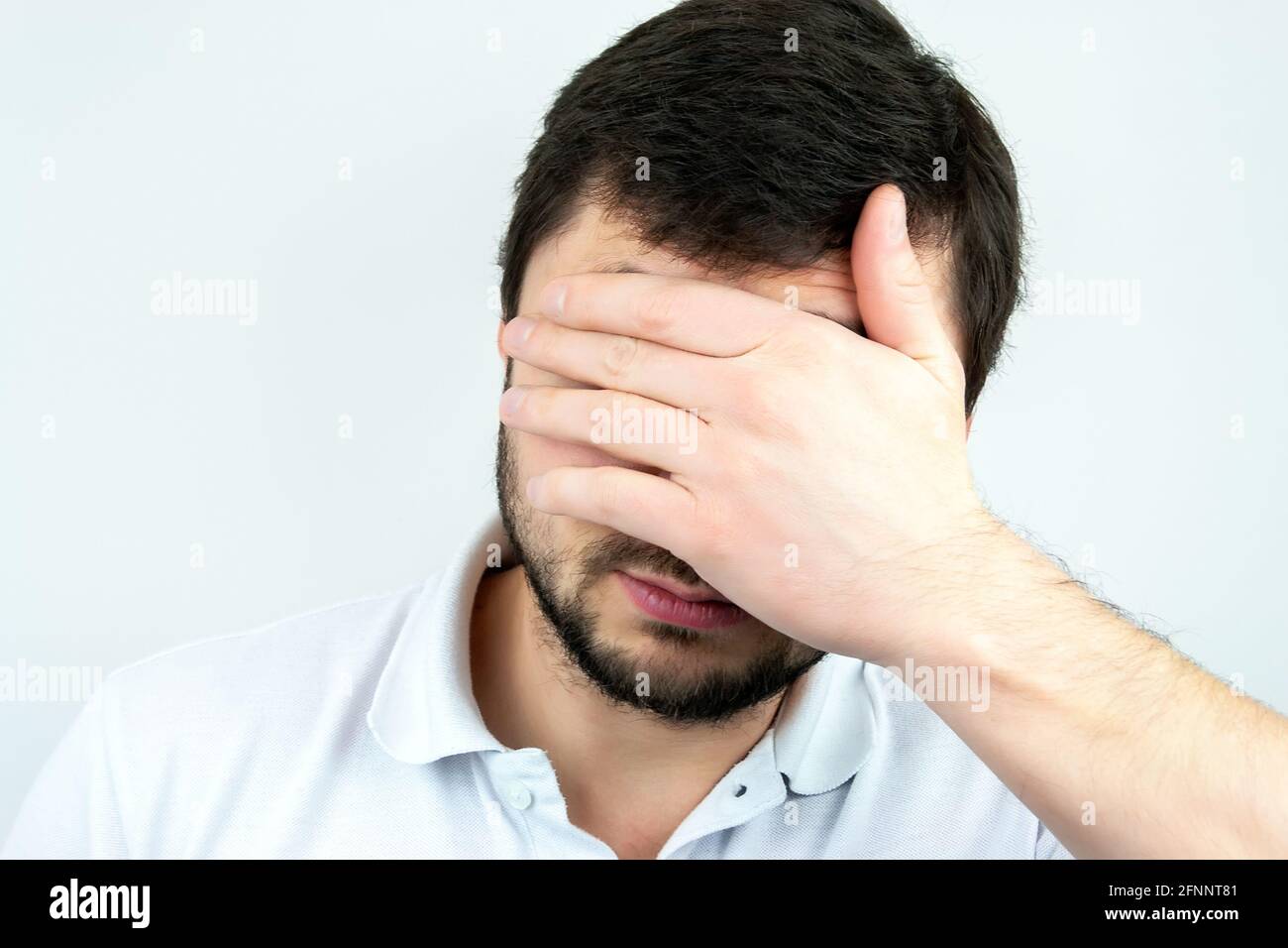 Closeup portrait of a bearded man holding palm over his face Stock Photo