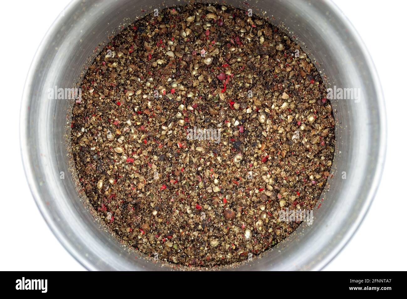 Modern steel pepper grinder with ground pepper mix isolated on white
