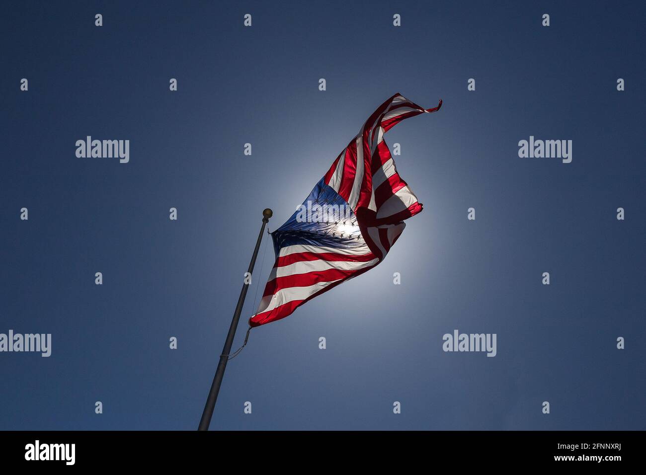 United States Flag with blue sky and sunlight. Stock Photo
