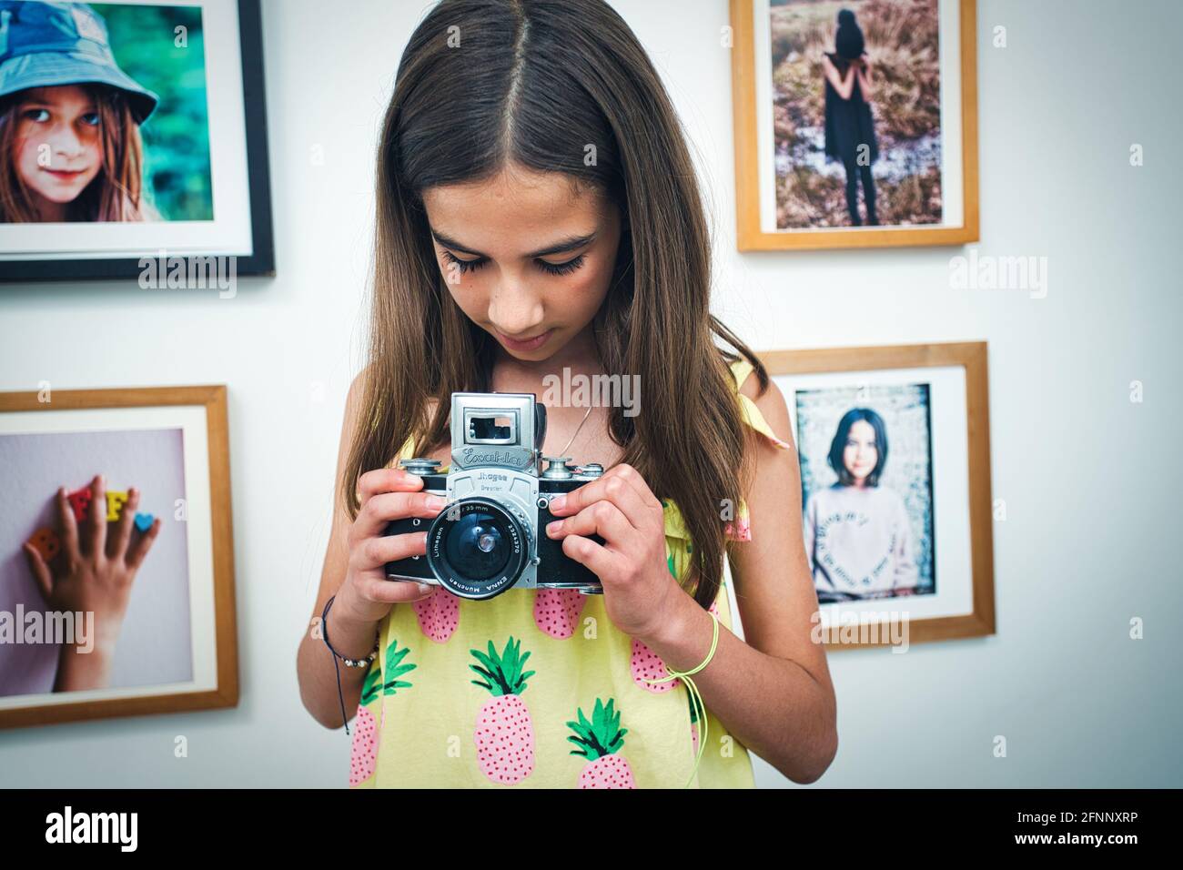 young girl holding vintage camera at home. Stock Photo
