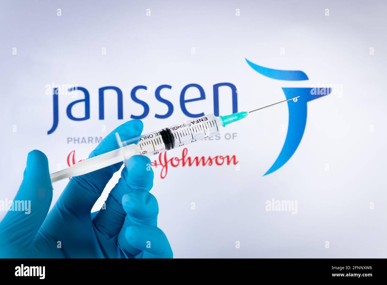 A hand holds a syringe in front of Janssen vaccine logo in Barcelona Spain, on May 18, 2021. Janssen is Covid-19 vaccine produced by the pharmaceutica Stock Photo