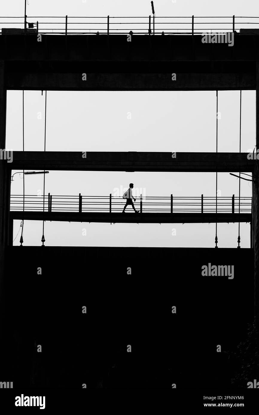 Silhouette shot of a man with a backpack walking on a bridge Stock ...