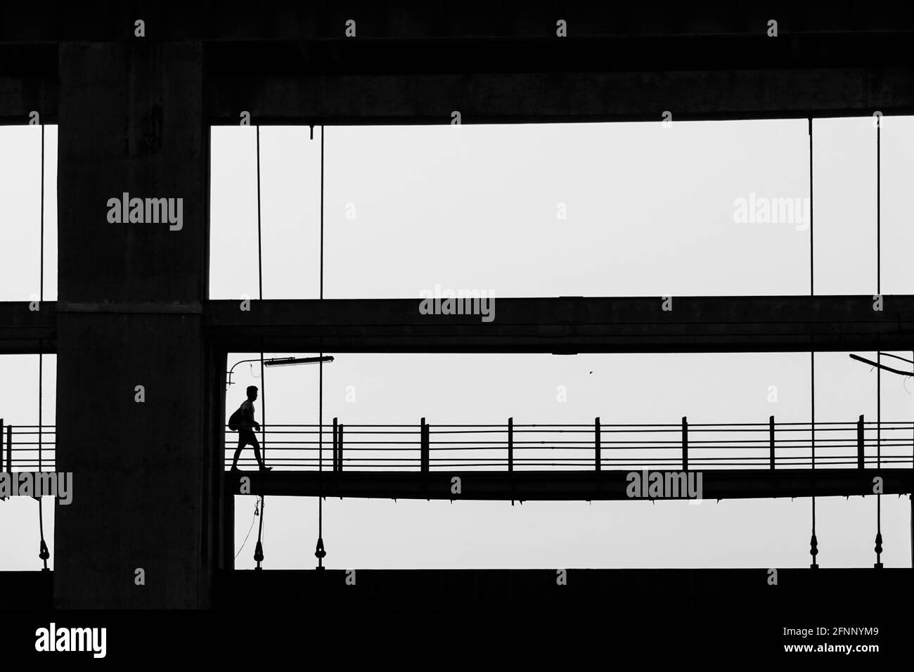 Silhouette shot of a man with a backpack walking on a bridge Stock ...