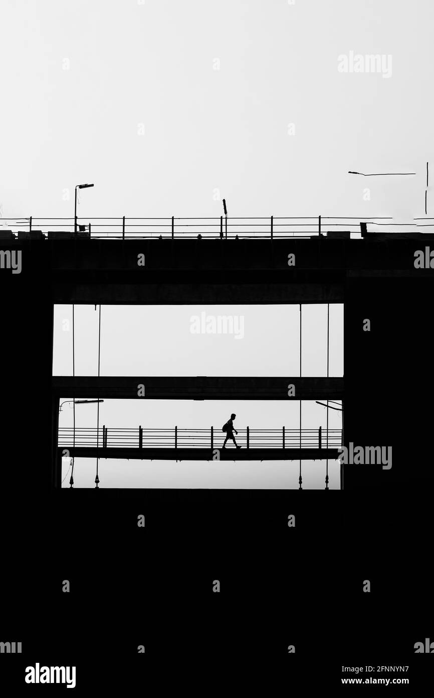 Silhouette shot of a man with a backpack walking on a bridge Stock ...