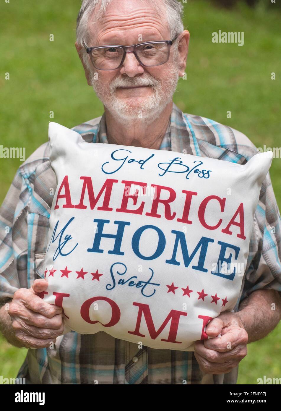 Elderly man holds a patriotic God Bless America pillow in honor of American Independence Day.. Stock Photo
