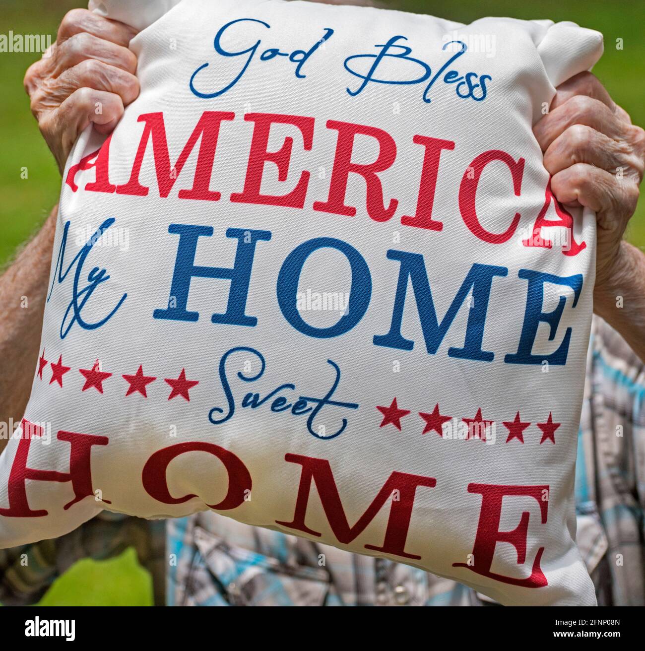 Elderly man holds a patriotic God Bless America pillow in honor of American Independence Day.. Stock Photo
