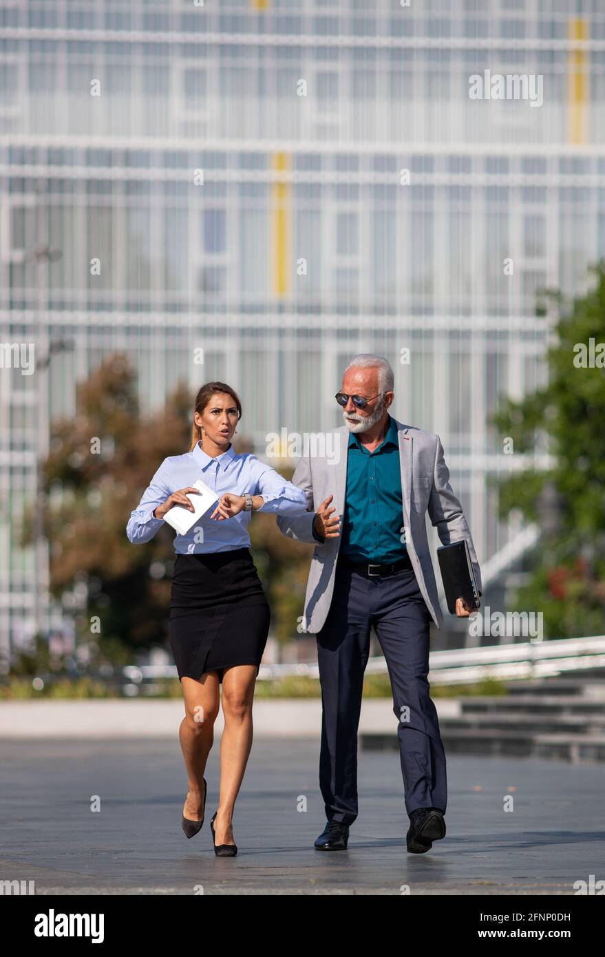 Business man and woman walking in rush on city square, running on meeting, being late and in hurry concept Stock Photo