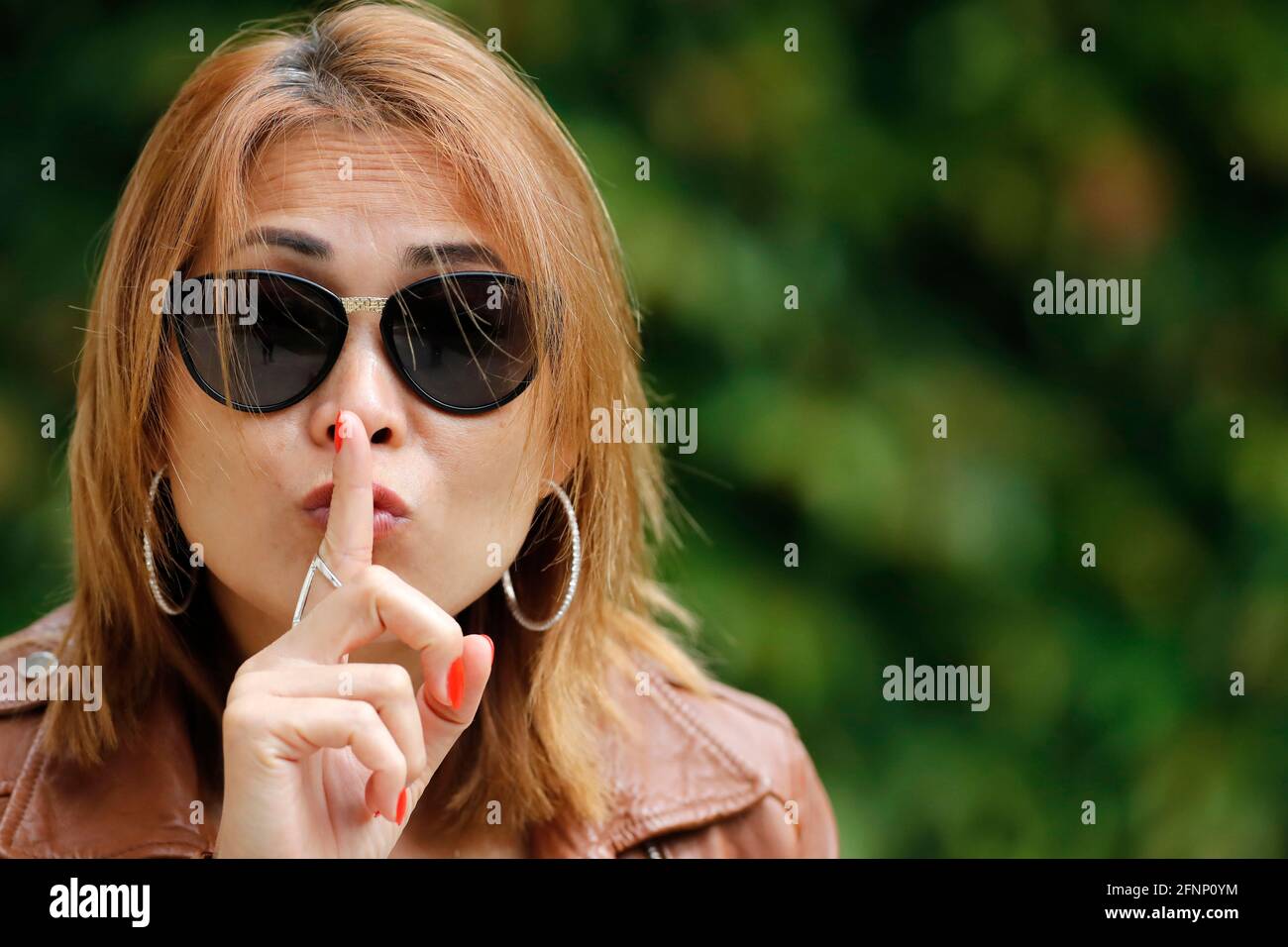 Woman showing the sign for silence with her index finger.  France. Stock Photo