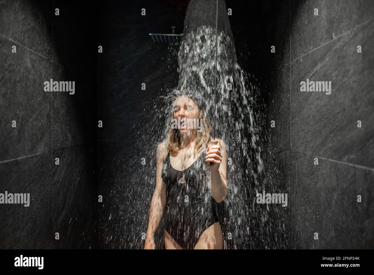 Woman hardening with bucket of ice cold water after hot sauna, healthy lifestyle and cold training concept. Wellness and spa. Stock Photo