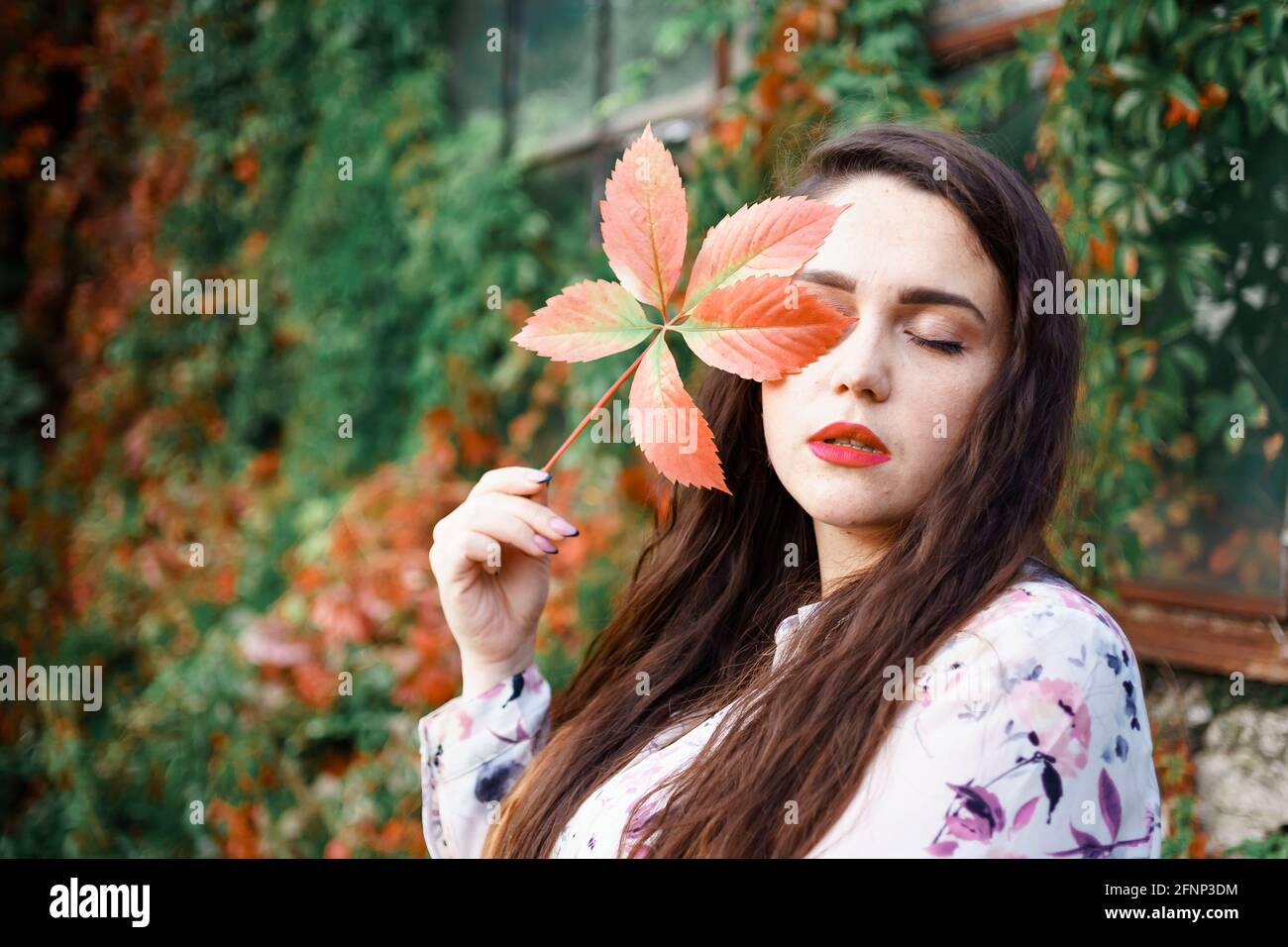 beautiful girl holding a leaf of wild grapes near her face Stock Photo ...