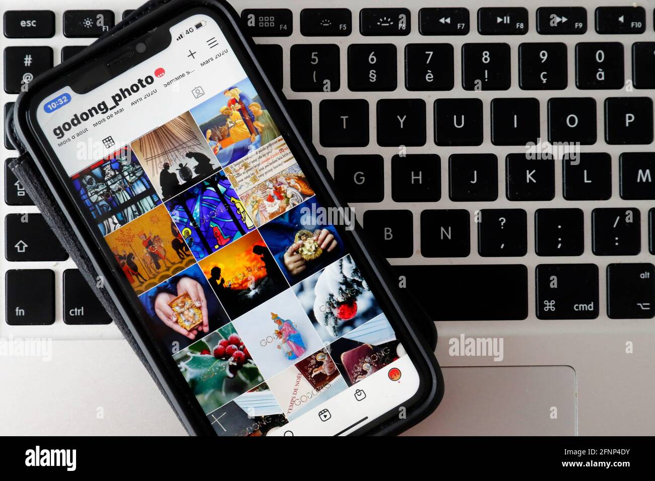 Iphone on a laptop  keyboard showing the explore page of the Instagram app with catholic images.  France. Stock Photo