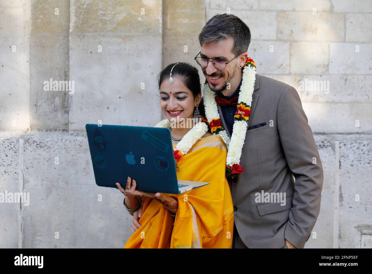Multiracial mariage in Paris, France. The newlyweds talk with their relatives via internet during the covid-19 pandemic. Stock Photo