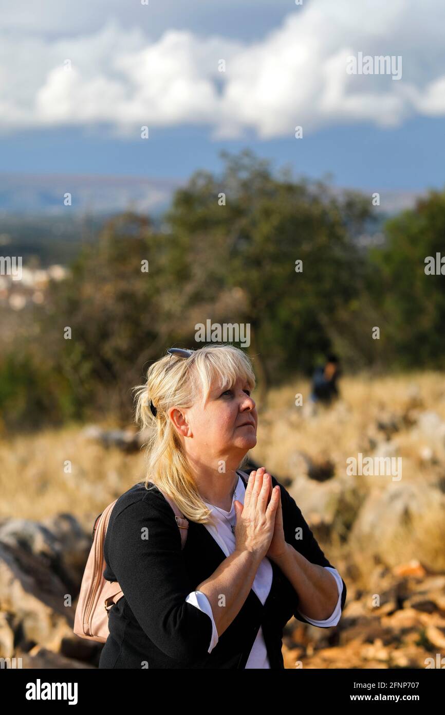 Pilgrim praying in front of the Virgin Mary statue on top of the the hill of apparitions, Podbrdo, Medjugorje, Bosnia and Herzegovina Stock Photo