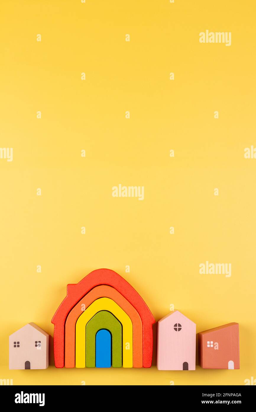 Small pastel color wooden houses and rainbow flag toy house on yellow  background Stock Photo - Alamy